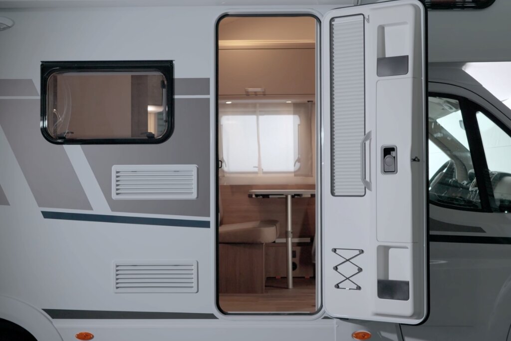 Offene Aufbautür am Carado Wohnmobil, Blick in Innenraum mit Sitzgruppe und Tisch