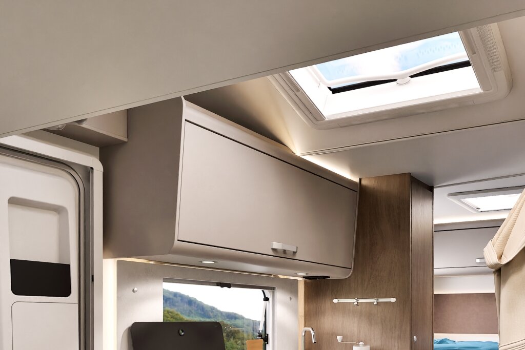 Innenraum Carado Wohnmobil mit Dachfenster, Hängeschrank und Blick zur Küche und Schlafbereich