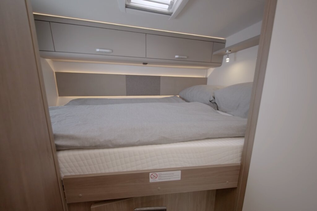 Schlafbereich im Carado Wohnmobil mit Doppelbett, Dachfenster und Oberschränken