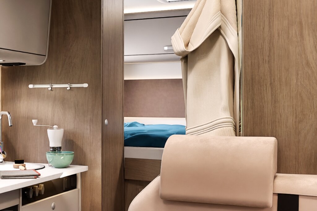 Innenraum Carado Wohnmobil mit Sitzbereich, Küchenzeile und Blick auf Bett im Heck