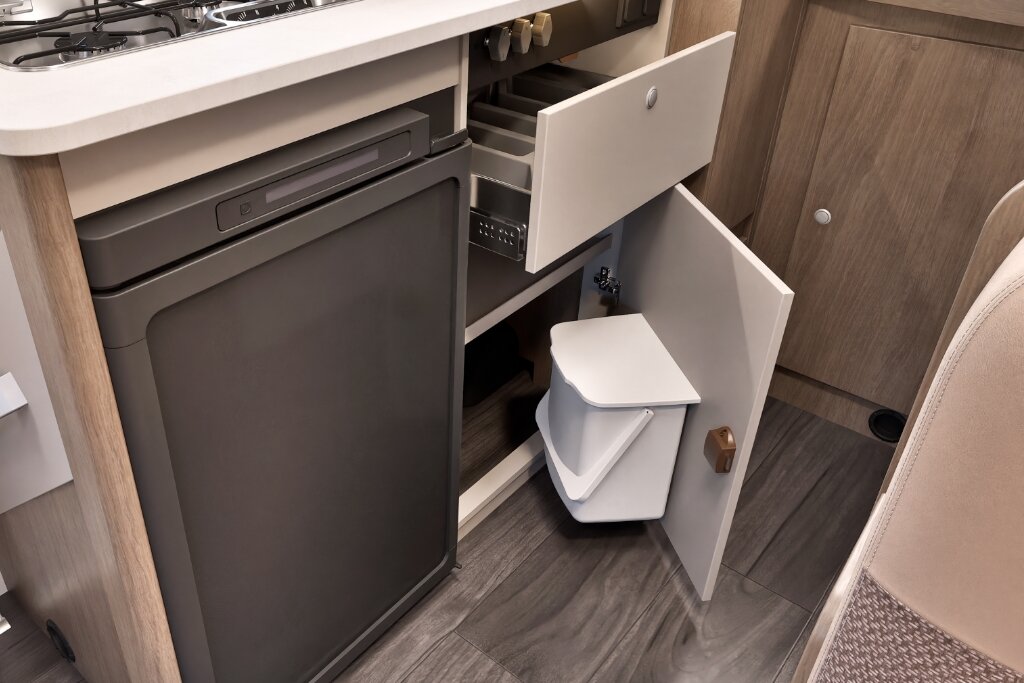 Küchenbereich im Carado Wohnmobil mit Kühlschrank, Schublade und Unterschrank mit integriertem Mülleimer
