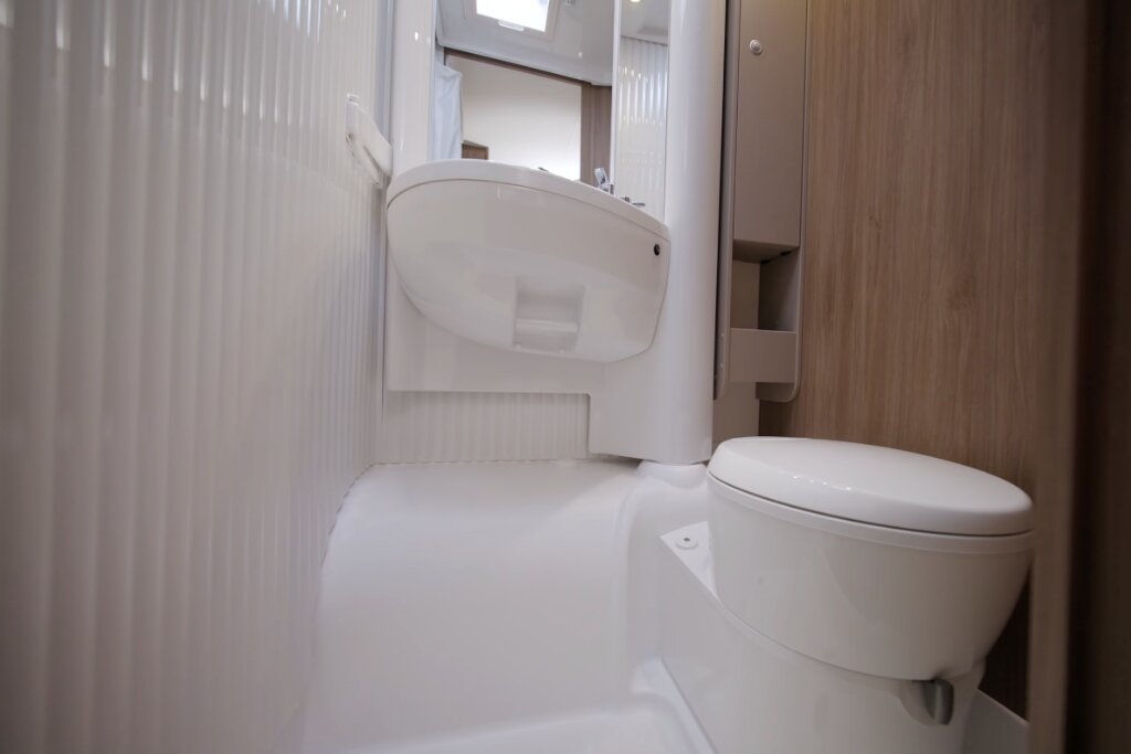 Bad im Carado Wohnmobil mit Toilette, Waschbecken und Holzschrank in kompakter Nasszelle