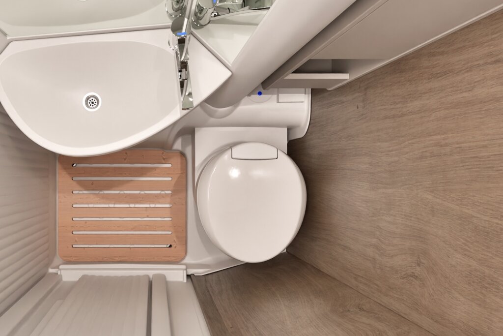Bad im Carado Wohnmobil mit Waschbecken, Kassettentoilette und Holzrost in der Dusche
