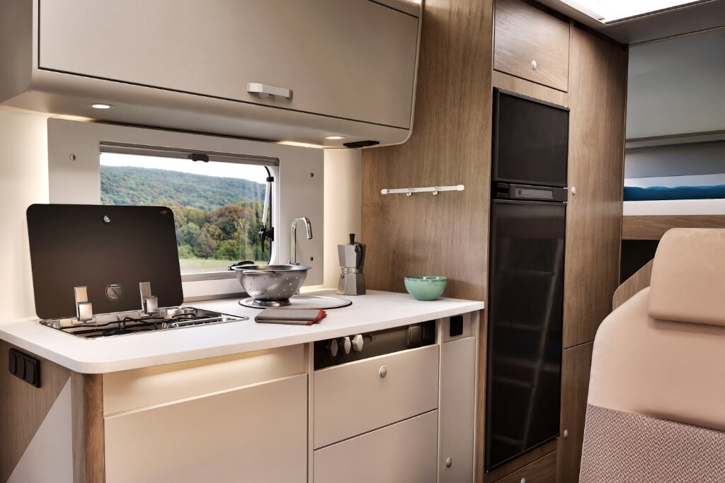 Küche im Carado Wohnmobil mit Gasherd, Spüle, Arbeitsfläche und hohem Kühlschrank