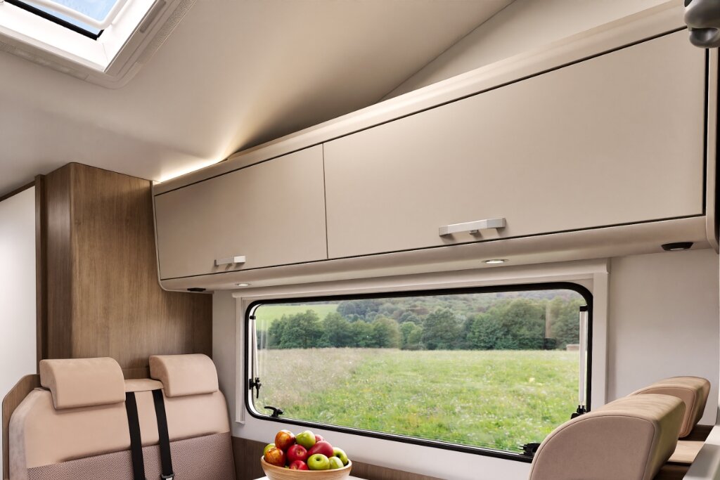 Innenraum Carado Wohnmobil mit Oberschränken, Dachfenster und Sitzgruppe am Seitenfenster