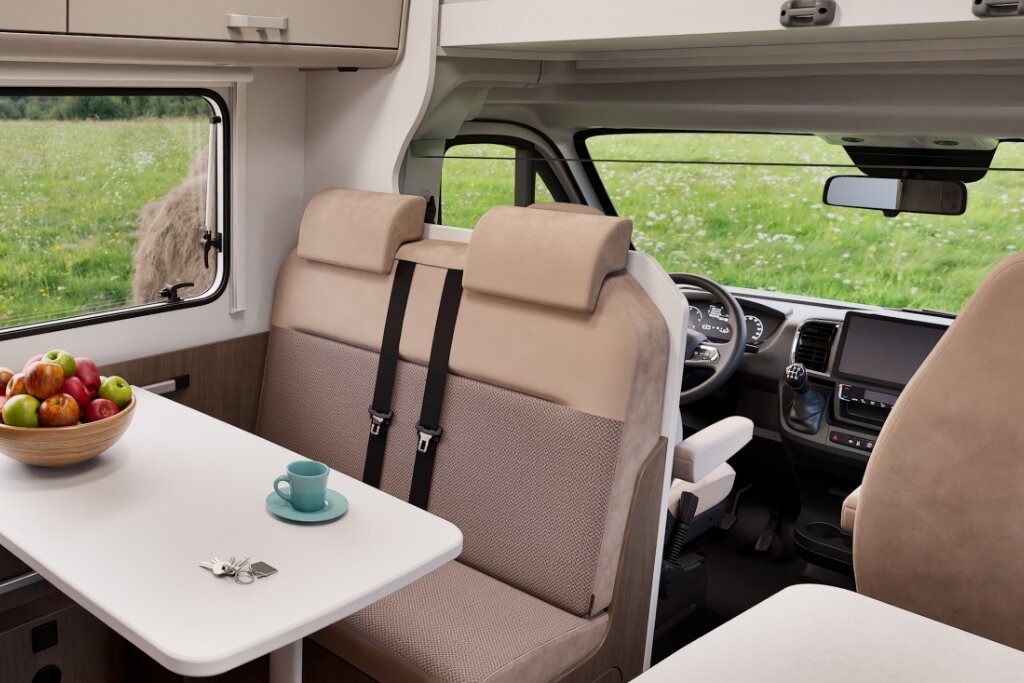 Innenraum Carado Wohnmobil mit Sitzgruppe, Tisch und Blick ins Fahrerhaus