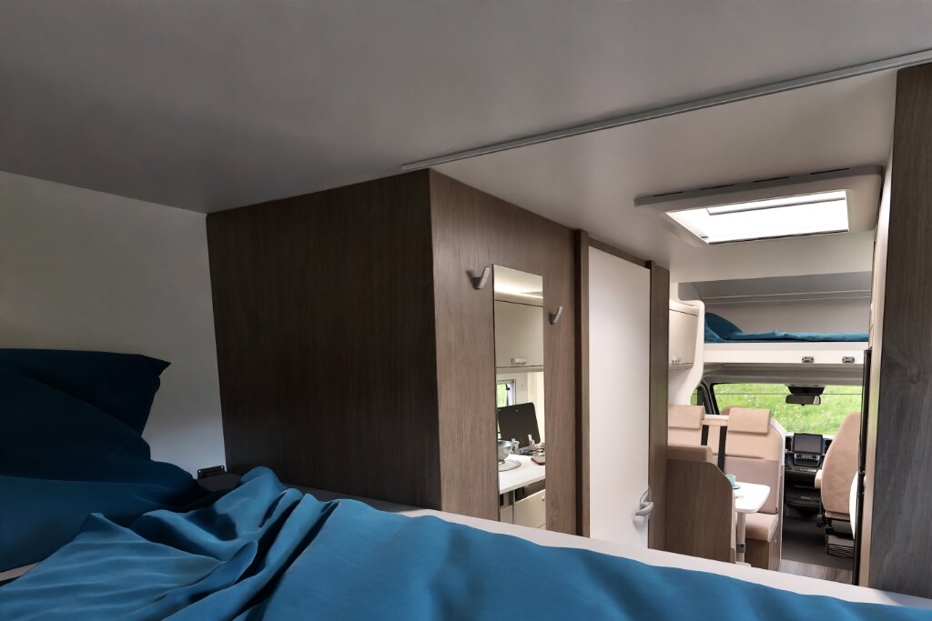 Innenraum Carado Wohnmobil mit Bett im Heck, Kleiderschrank, Dachfenster und Blick nach vorn zur Sitzgruppe