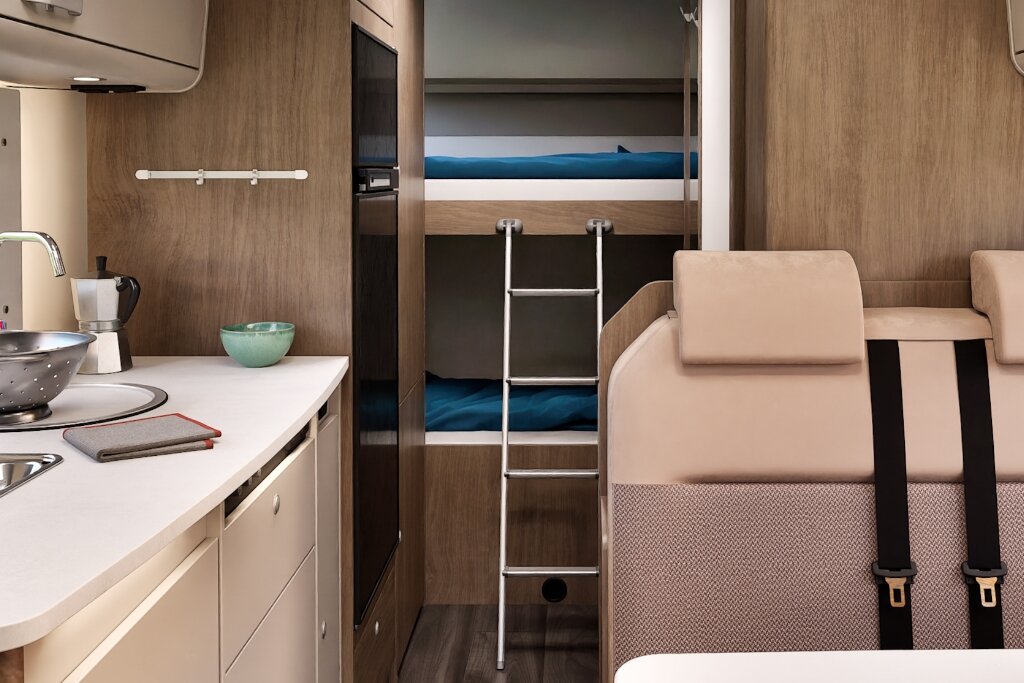 Innenraum Carado Wohnmobil mit Küche, Sitzbank und Etagenbett mit Leiter im Heck