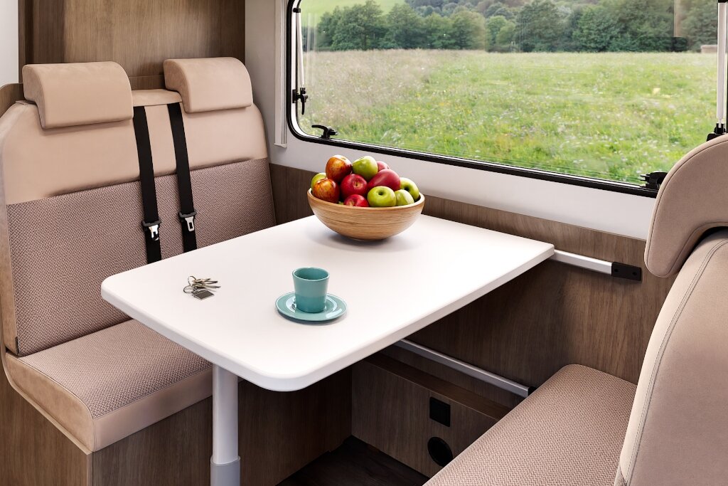Sitzgruppe im Carado Wohnmobil mit Tisch, Obstschale und Fensterblick ins Grüne