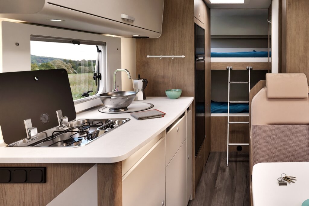 Innenraum Carado Wohnmobil mit Küche, Gasherd, Spüle und Etagenbetten im Heck