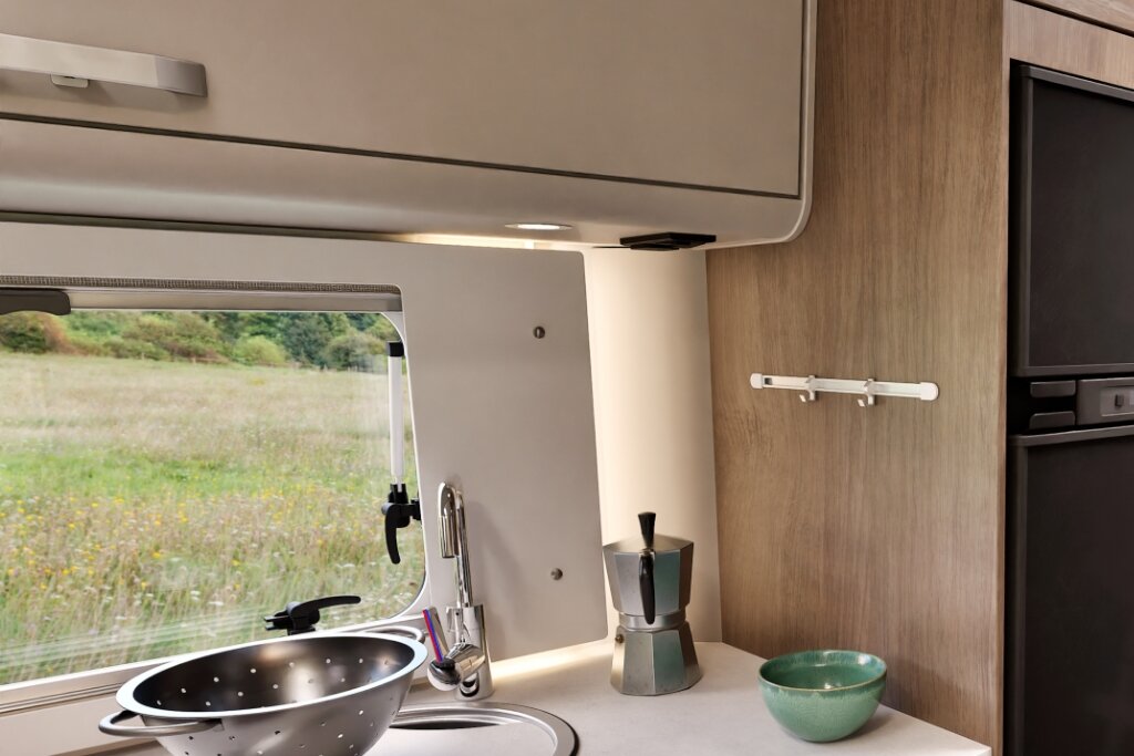 Küchenbereich im Carado Wohnmobil mit Spüle, Oberschrank, Fenster und Kühlschrank