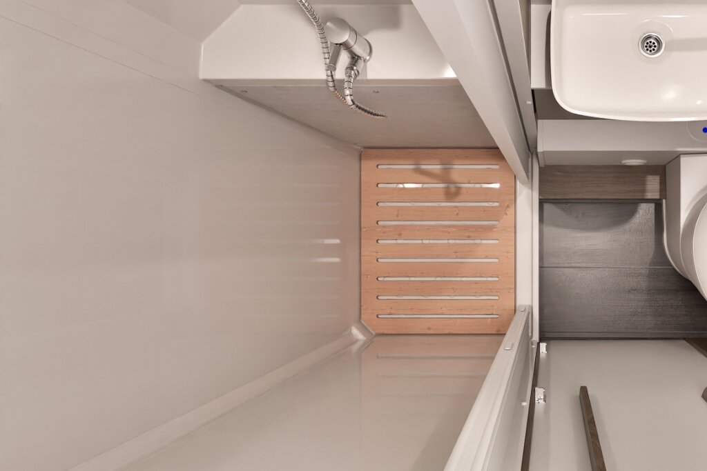 Bad im Carado Wohnmobil mit Waschbecken, Toilette und Duschbereich mit Holzrost