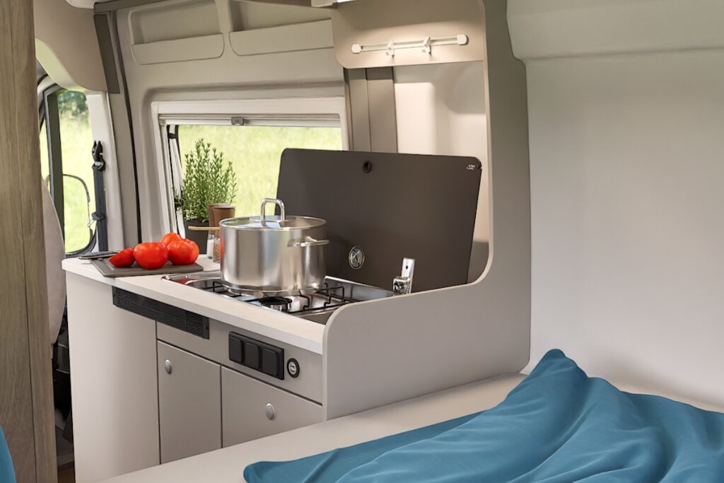 Innenraum Carado Wohnmobil mit Küche, Gasherd, Kochtopf und Bett im Vordergrund