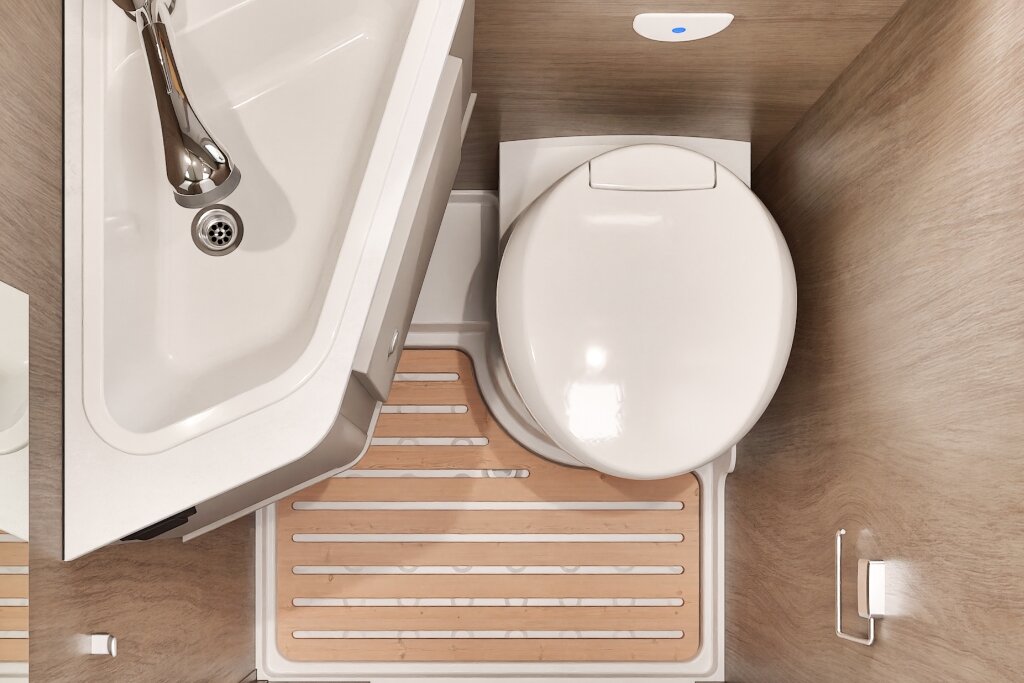 Badezimmer im Carado Wohnmobil mit Waschbecken, Kassettentoilette und Duschboden in Holzoptik