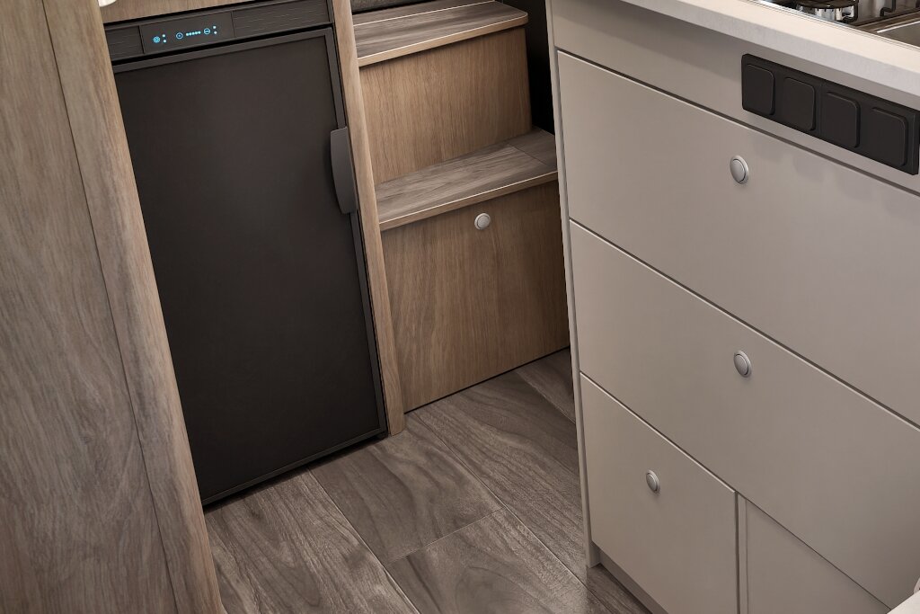 Küchenbereich im Carado Wohnmobil mit Kühlschrank, Schubladen und Holzregal