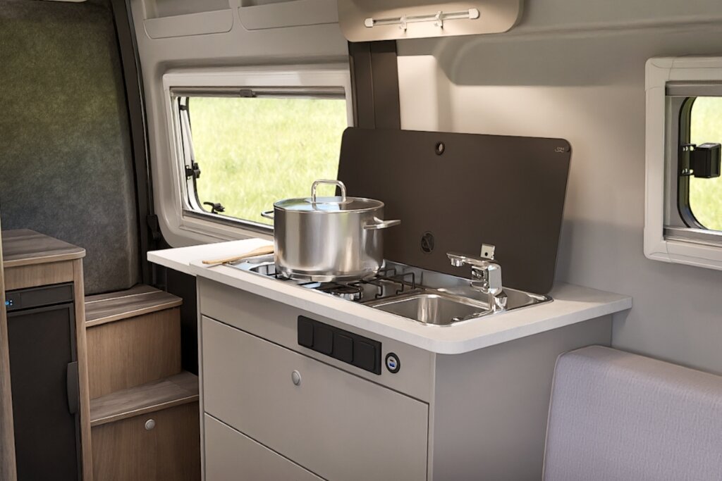 Küche im Carado Wohnmobil mit Gasherd, Spüle und Kochtopf auf der Arbeitsfläche