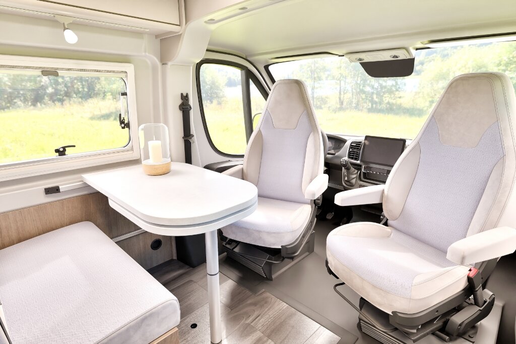Innenraum Carado Wohnmobil mit Sitzgruppe, Tisch und drehbaren Fahrerhaussitzen