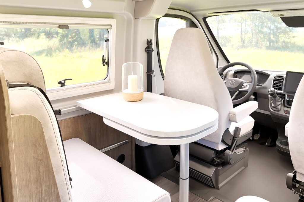 Innenraum Carado Wohnmobil mit Sitzgruppe, Tisch und gedrehten Fahrerhaussitzen