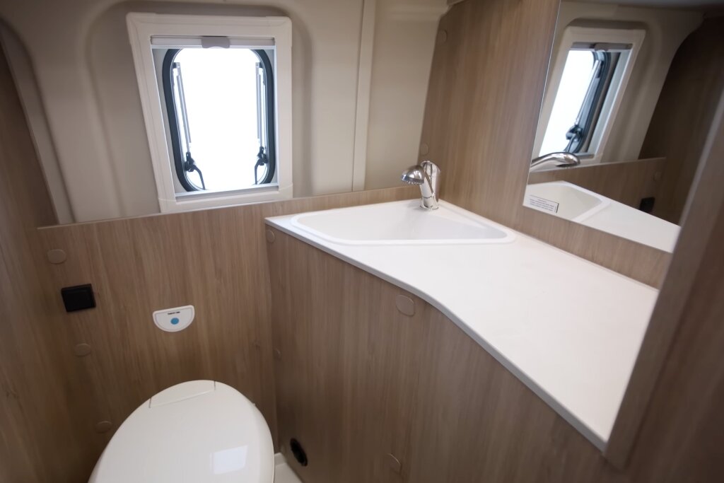 Bad im Carado Wohnmobil mit Waschbecken, Spiegel, Toilette und Fenster