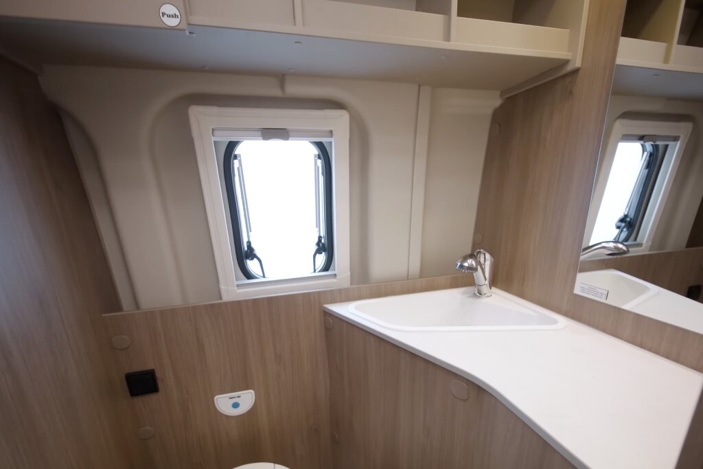 Bad im Carado Wohnmobil mit Waschbecken, Spiegel, Fenster und Holzdekor
