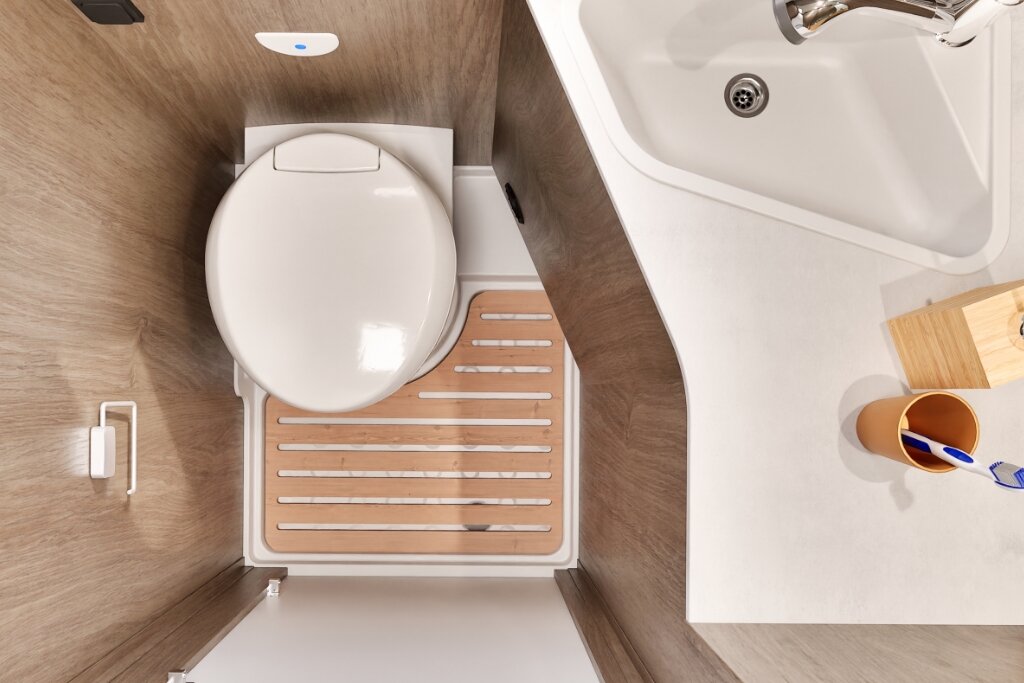 Bad im Carado Wohnmobil mit Toilette, Waschbecken und Holzrost in der Dusche