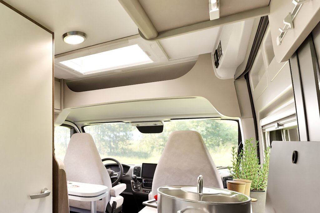 Innenraum Carado Wohnmobil mit Fahrerhaus, Dachfenster und Küchenbereich mit Topf im Vordergrund