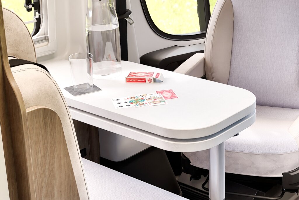 Sitzgruppe im Carado Wohnmobil mit Tisch, Wasserflasche, Glas und Spielkarten