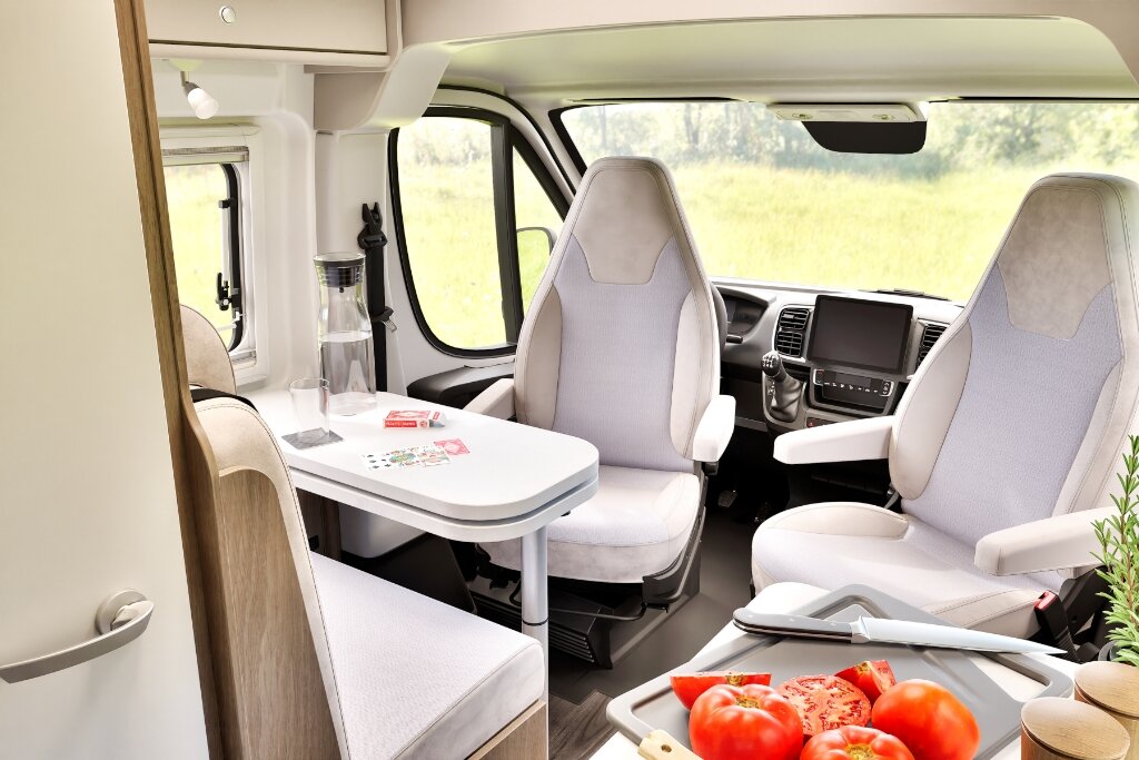 Innenraum Carado Wohnmobil mit Sitzgruppe, drehbaren Fahrersitzen und Tisch im vorderen Wohnbereich
