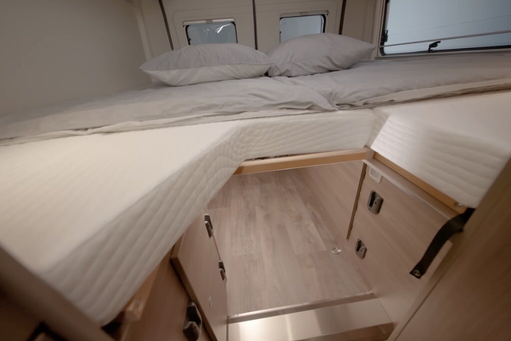Schlafbereich im Carado Wohnmobil mit hochgeklappten Matratzen und Stauraum unter dem Bett
