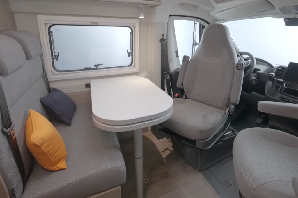 Sitzgruppe im Carado Wohnmobil mit Tisch, Seitenbank und drehbaren Fahrerhaussitzen