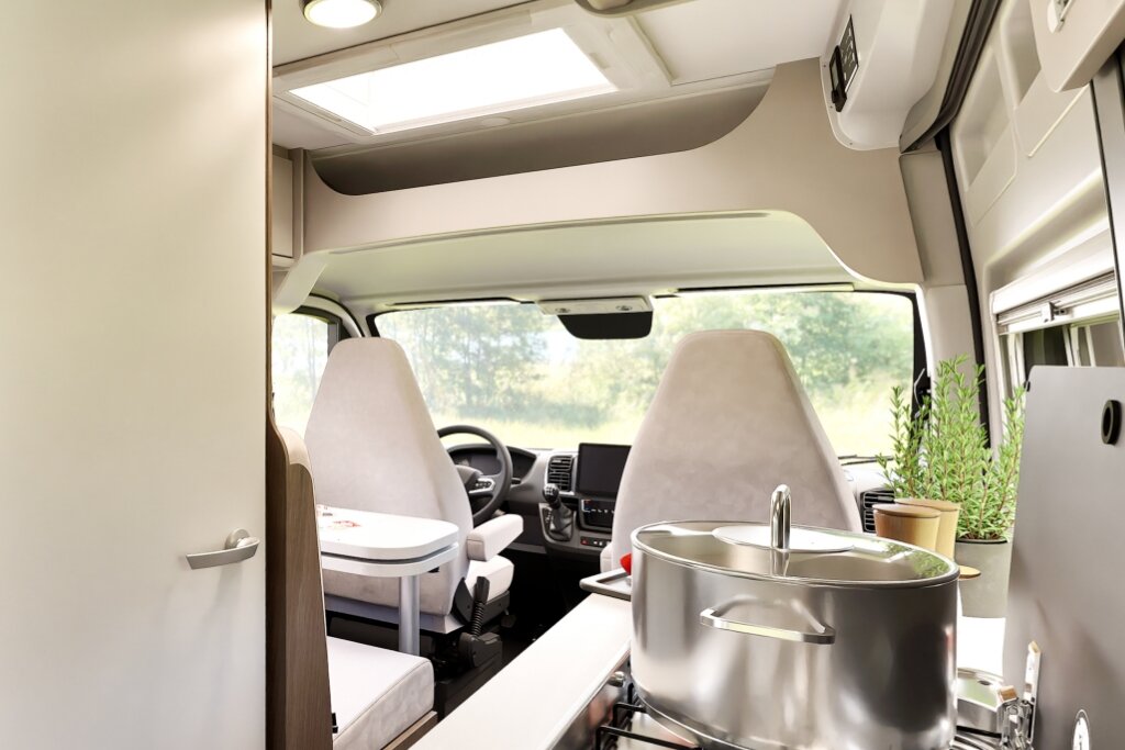 Innenraum Carado Wohnmobil mit Fahrerhaus, Dachfenster und Küchenbereich mit Kochtopf und Spüle