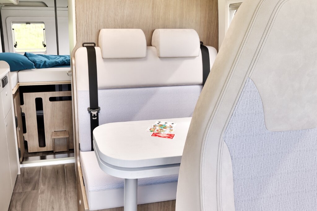 Innenraum Carado Wohnmobil mit Sitzgruppe, Tisch und Bett im Heck