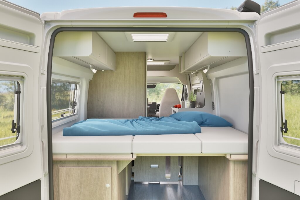 Heckbett im Carado Wohnmobil, Blick durch geöffnete Hecktüren in den hellen Schlafbereich
