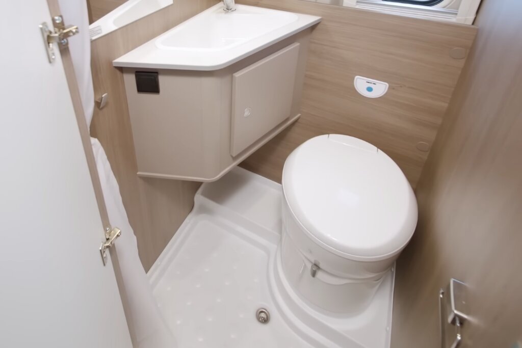 Bad im Carado Wohnmobil mit Toilette, Waschbecken und Duschwanne in kompakter Holzoptik