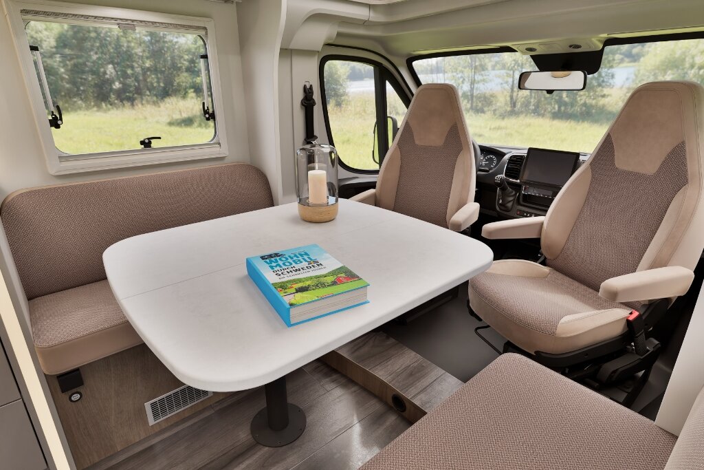 Sitzgruppe im Carado Wohnmobil mit Tisch, Seitenbank und drehbaren Fahrerhaussitzen