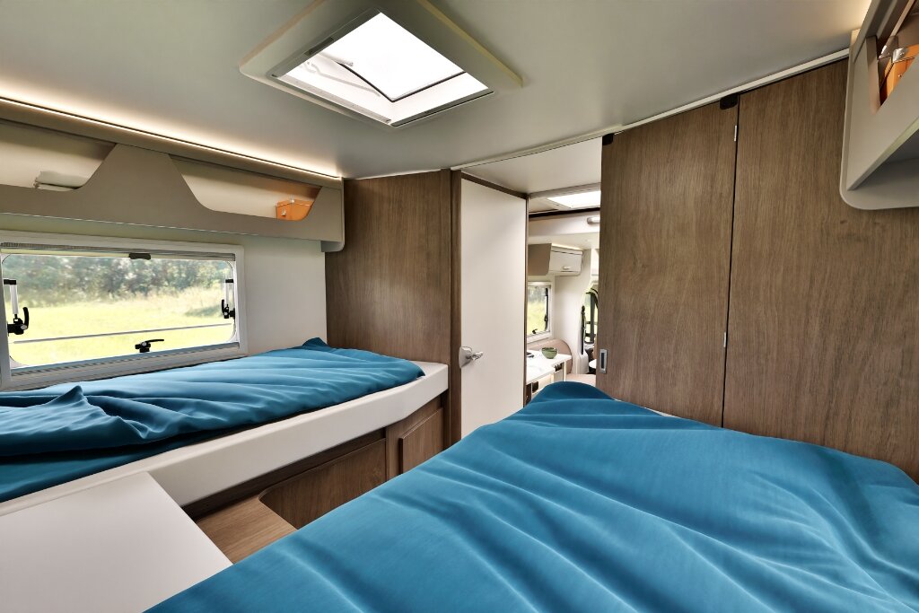 Schlafbereich im Carado Wohnmobil mit zwei Betten, Dachfenster und Holzschrank