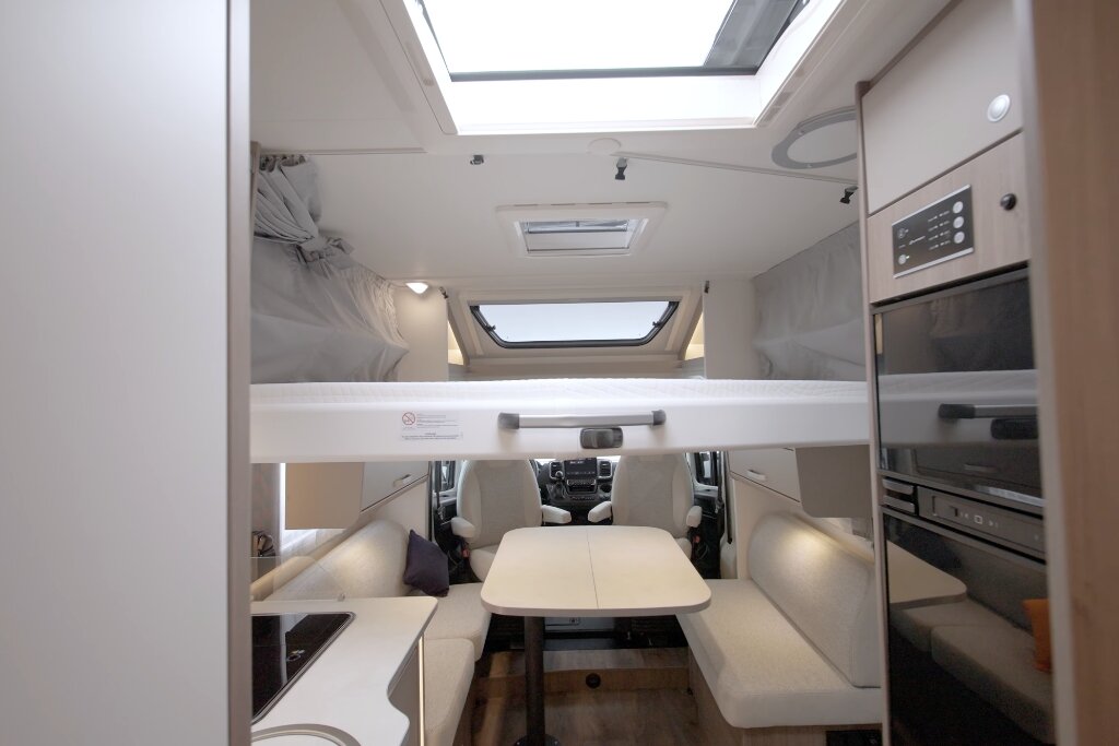 Innenraum Carado Wohnmobil mit Hubbett, Sitzgruppe und Küche im vorderen Bereich