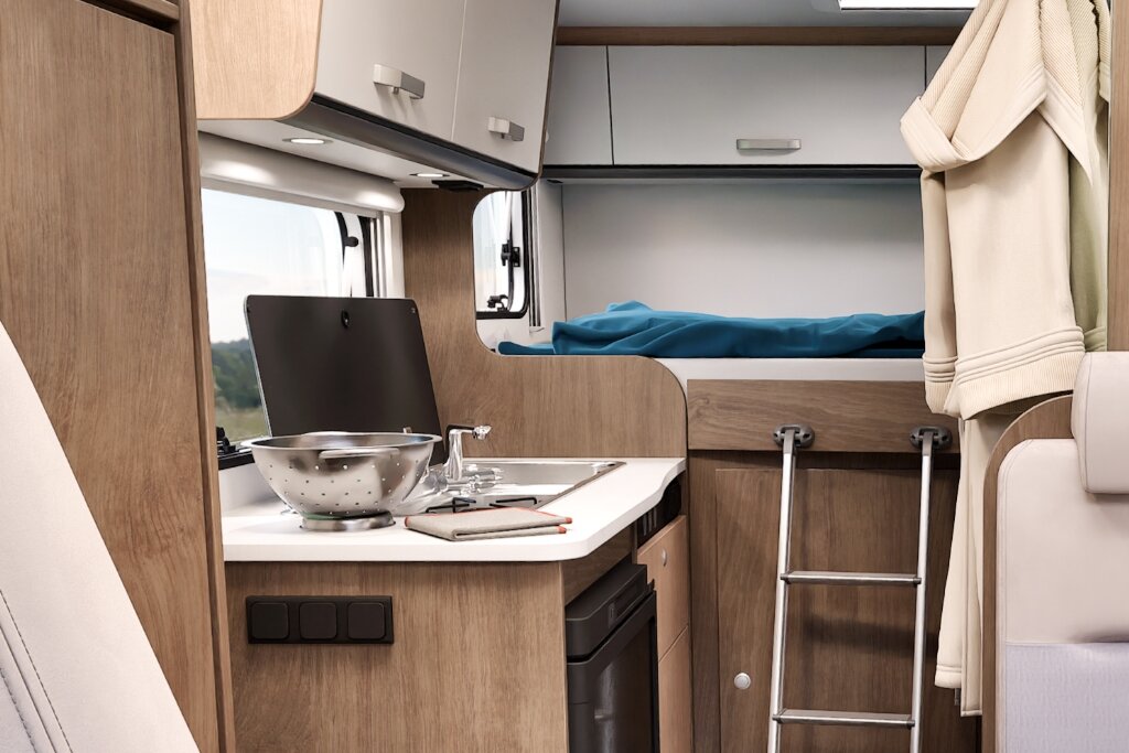 Innenraum Carado Wohnmobil mit Küchenzeile, Spüle und hinterem Bett mit Leiter