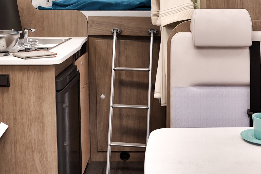Innenraum Carado Wohnmobil mit Küche, Leiter zum Bett und Sitzbank