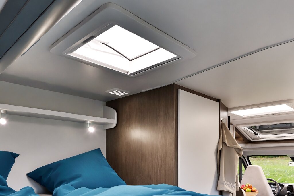 Schlafbereich im Carado Wohnmobil mit Bett, Dachfenstern, Leselicht und Hochschrank