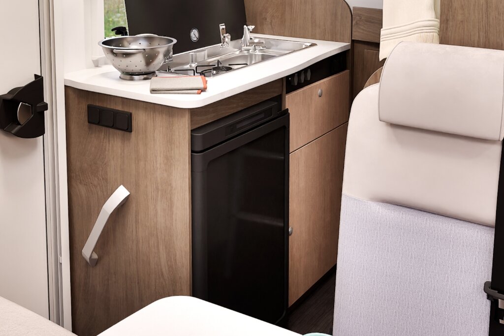Küche im Carado Wohnmobil mit Spüle, Gasherd, Kühlschrank und Holzdekor