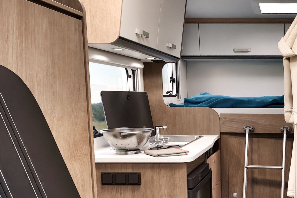Innenraum Carado Wohnmobil mit Küchenzeile, Spüle, Arbeitsfläche und Heckbett mit Leiter