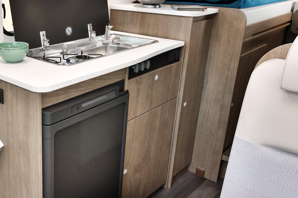 Küche im Carado Wohnmobil mit Spüle, Gasherd, Kühlschrank und Holzschränken