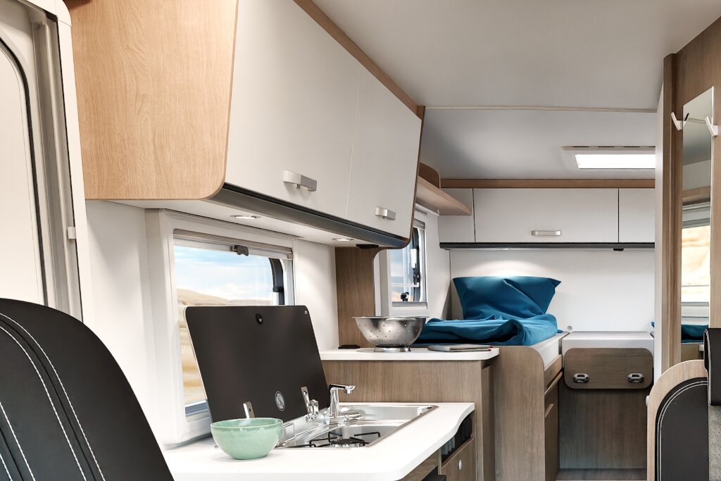 Innenraum Carado Wohnmobil mit Küche, Hängeschränken und Einzelbett im Heck