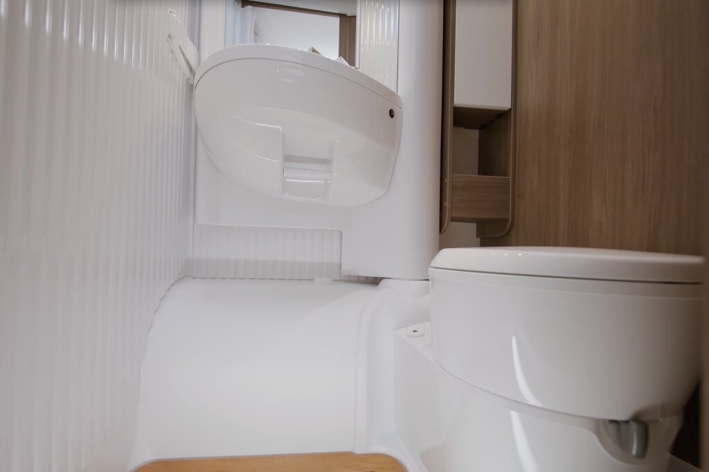 Badezimmer im Carado Wohnmobil mit Waschbecken, Toilette und Holzschrank
