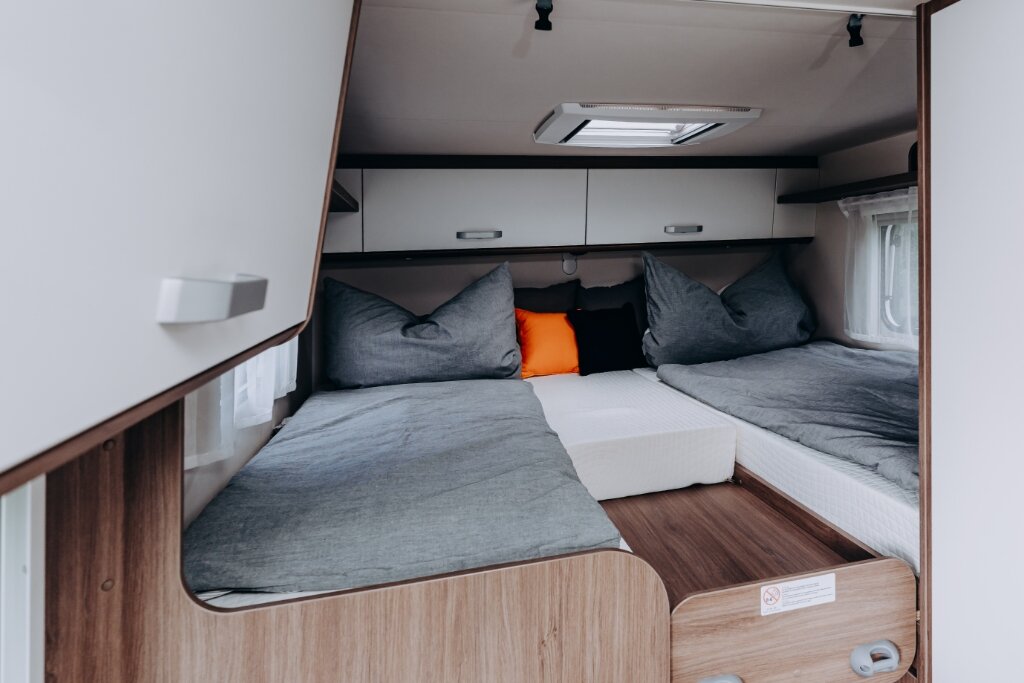 Schlafbereich im Carado Wohnmobil mit zwei Einzelbetten, Dachfenster und Oberschränken