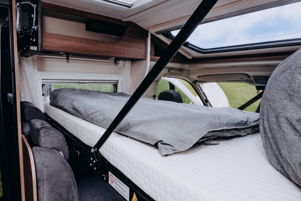 Schlafbereich im Carado Wohnmobil mit Hubbett, Matratze und geöffnetem Dachfenster