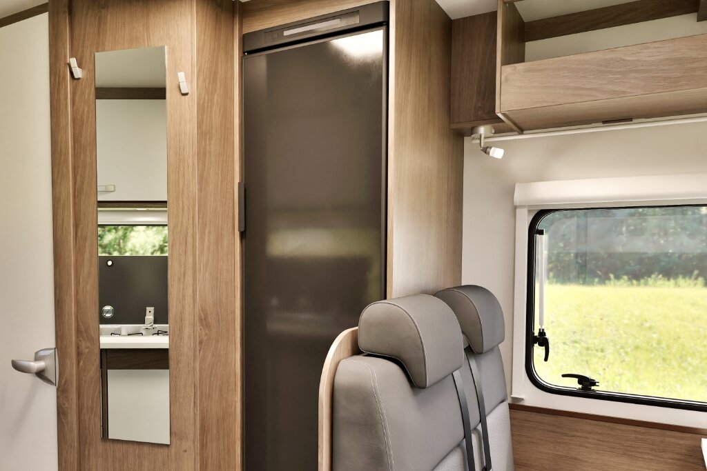 Innenraum Carado Wohnmobil mit Kühlschrank, Spiegel, Sitzbank und Fenster neben dem Küchenbereich