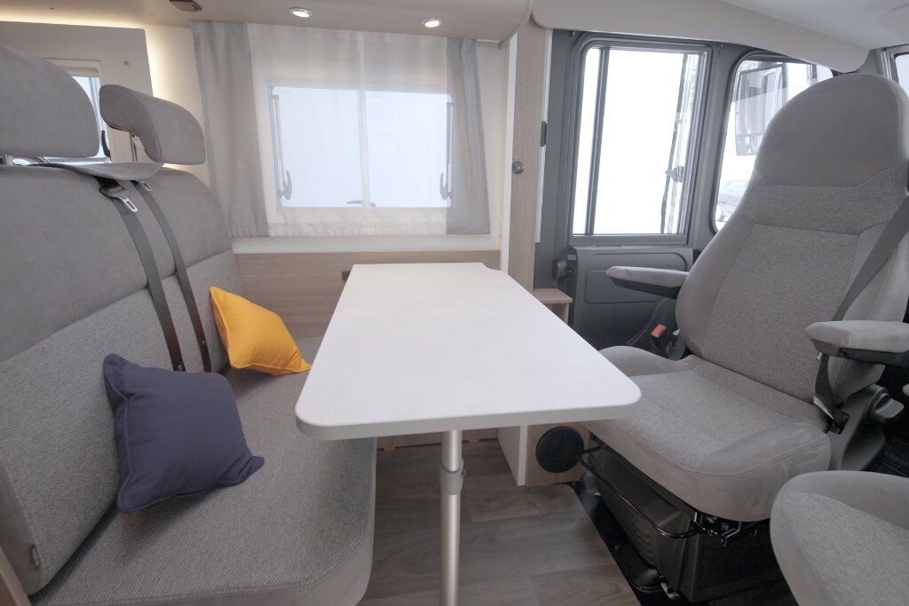 Seating area in the Carado motorhome with table, longitudinal bench and swivel driver’s seat in the bright interior
