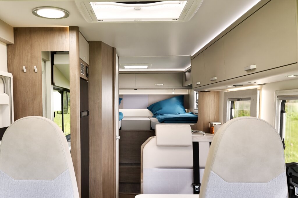 Carado motorhome interior with cab seats, overhead cabinets and rear bed